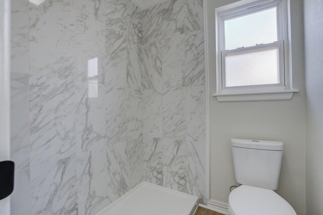 bathroom with tiled shower and toilet