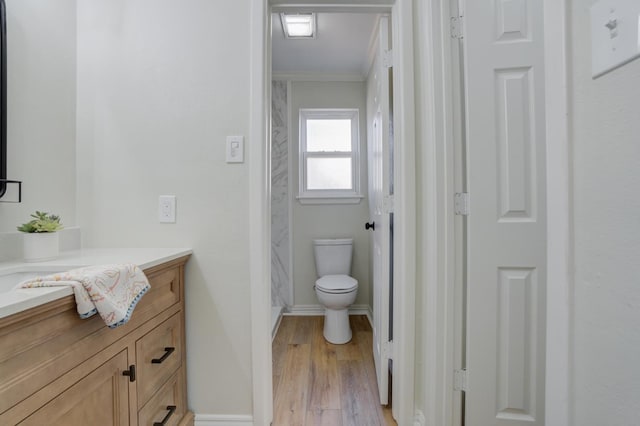 bathroom with hardwood / wood-style flooring, ornamental molding, vanity, and toilet