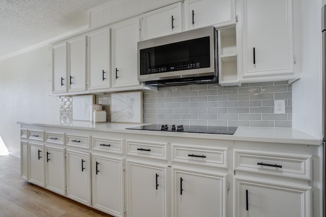 kitchen with white cabinetry, black electric stovetop, and light hardwood / wood-style flooring