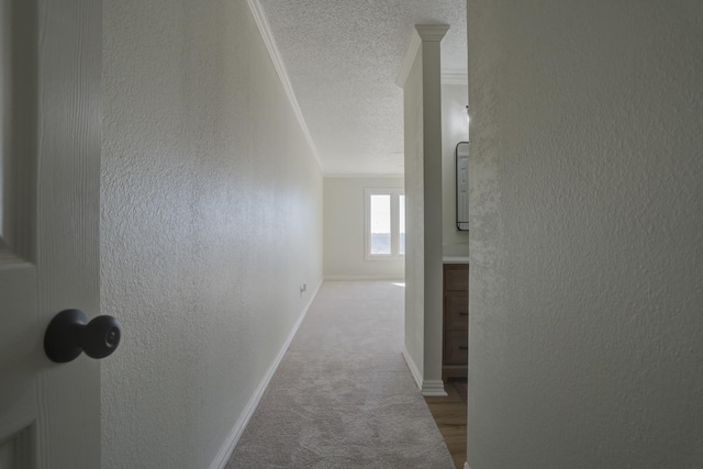 corridor with ornamental molding, light colored carpet, and a textured ceiling