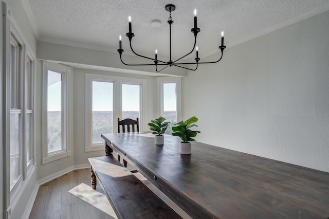 dining area featuring hardwood / wood-style flooring, crown molding, a textured ceiling, and a notable chandelier