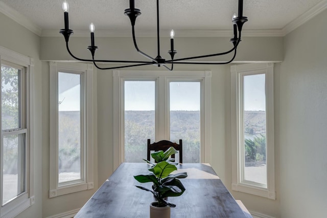 dining space featuring ornamental molding, a textured ceiling, and a notable chandelier