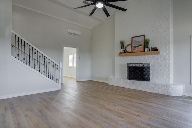 unfurnished living room with an AC wall unit, beamed ceiling, ceiling fan, a brick fireplace, and light hardwood / wood-style flooring