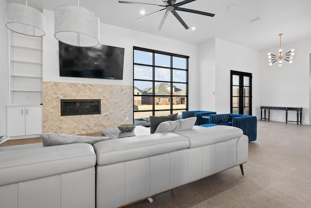 living room featuring ceiling fan with notable chandelier, a fireplace, and built in features