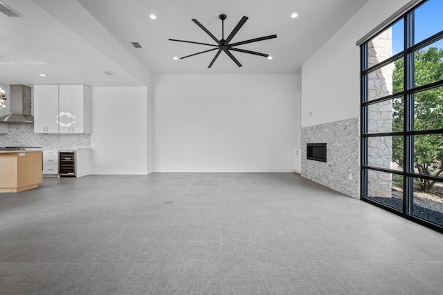 unfurnished living room with wine cooler, a fireplace, and a chandelier