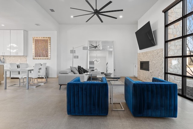 living room with ceiling fan with notable chandelier and a fireplace