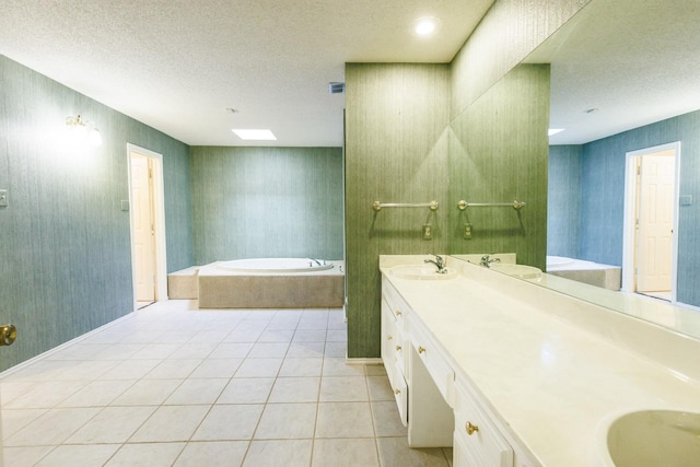 bathroom featuring a relaxing tiled tub, tile patterned floors, vanity, and a textured ceiling