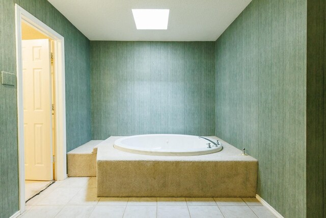 bathroom with a skylight, tile patterned flooring, and tiled tub