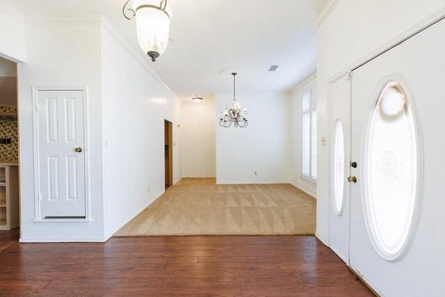 foyer entrance with dark hardwood / wood-style flooring, crown molding, and a chandelier