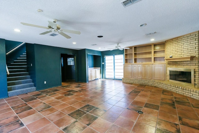 unfurnished living room featuring a textured ceiling, built in features, dark tile patterned floors, ceiling fan, and a fireplace