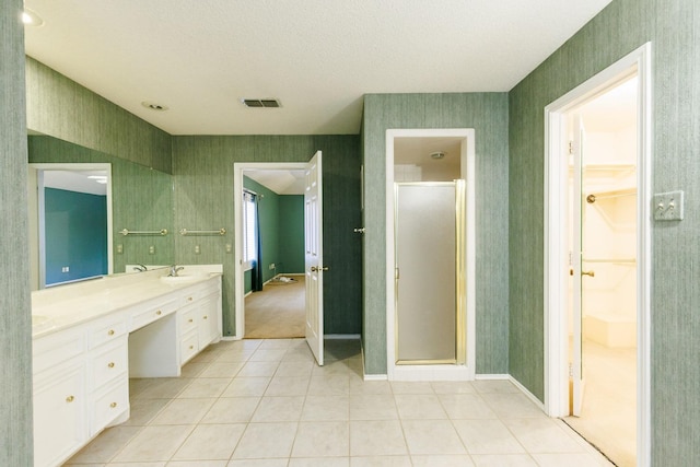 bathroom with an enclosed shower, vanity, tile patterned flooring, and a textured ceiling