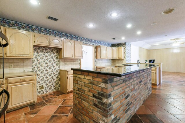 kitchen featuring light brown cabinetry, tasteful backsplash, a center island, a textured ceiling, and ceiling fan