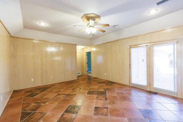 unfurnished room with ceiling fan, lofted ceiling, a textured ceiling, and wood walls