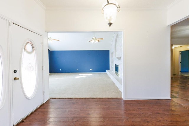 foyer featuring crown molding, vaulted ceiling, dark hardwood / wood-style flooring, ceiling fan, and a fireplace