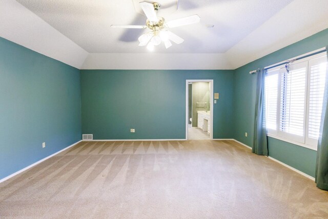 unfurnished bedroom with light carpet, vaulted ceiling, ceiling fan, and ensuite bathroom