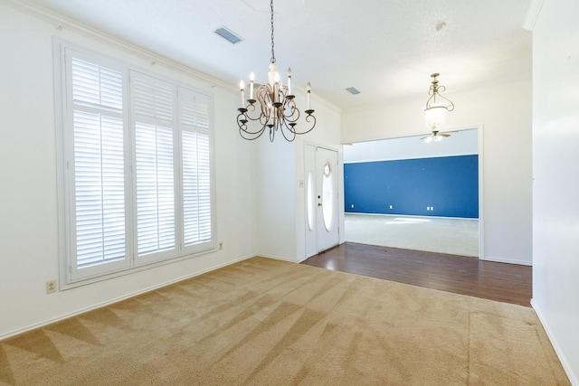 carpeted spare room with ornamental molding and a chandelier