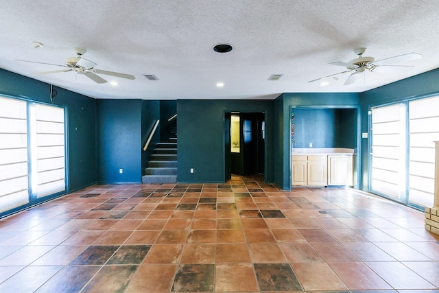 unfurnished living room with a healthy amount of sunlight, a textured ceiling, and ceiling fan