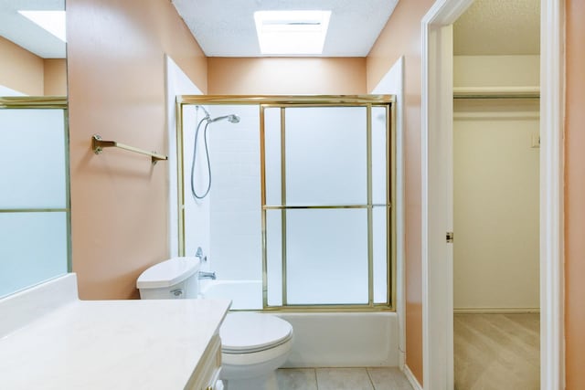 full bathroom with shower / bath combination with glass door, vanity, toilet, tile patterned floors, and a textured ceiling