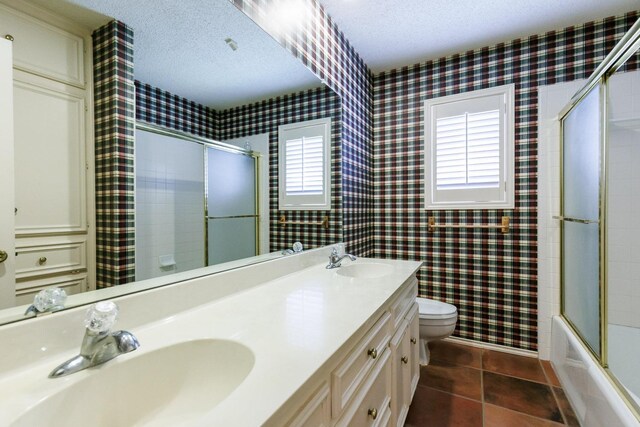 full bathroom featuring tile patterned flooring, vanity, a textured ceiling, and toilet