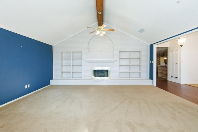 unfurnished living room with ceiling fan, carpet flooring, a fireplace, lofted ceiling with beams, and built in shelves