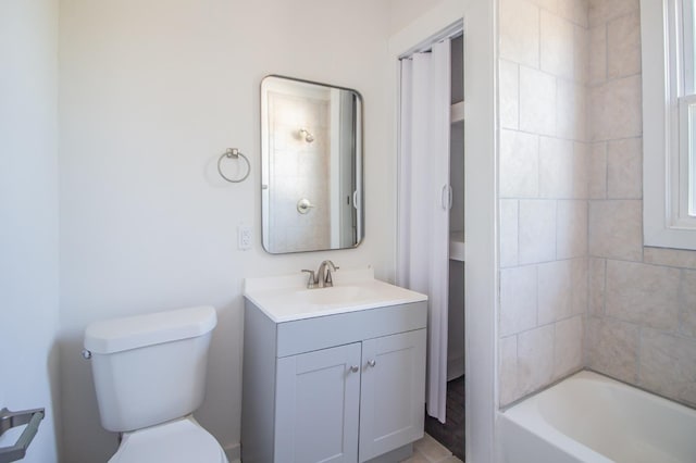 full bathroom featuring tiled shower / bath, vanity, and toilet