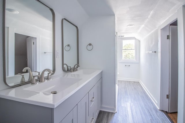 bathroom featuring vanity, vaulted ceiling, and wood-type flooring