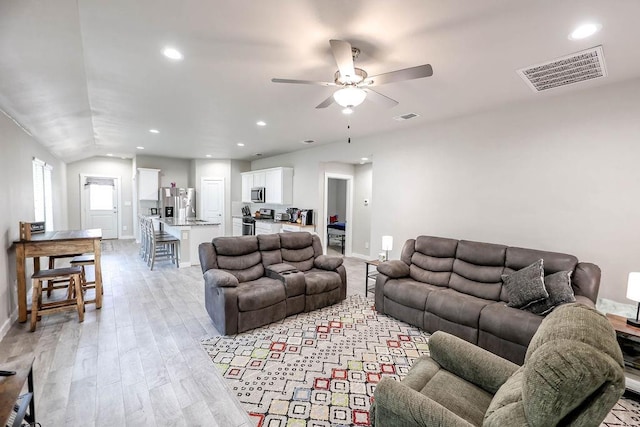 living room featuring ceiling fan, lofted ceiling, and light hardwood / wood-style floors