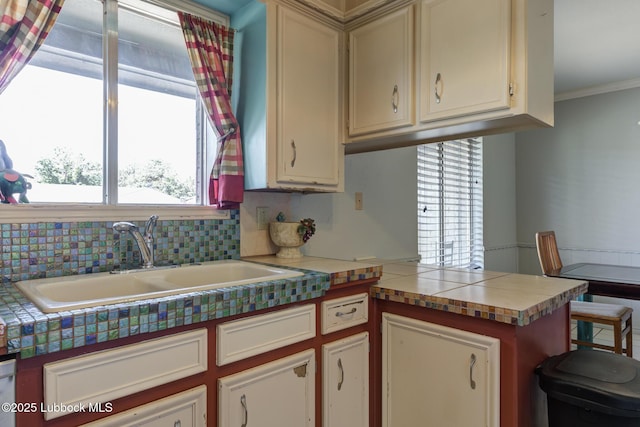 3312 86th St, Lubbock, TX 79423 - kitchen featuring a sink, a peninsula, crown molding, and tasteful backsplash
