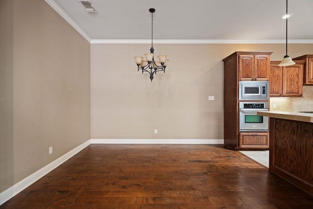 kitchen featuring pendant lighting, stainless steel appliances, crown molding, and hardwood / wood-style flooring