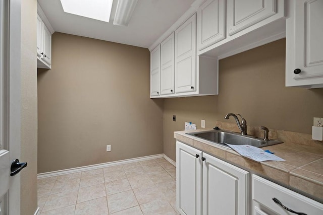 washroom featuring light tile patterned flooring, sink, cabinets, a skylight, and hookup for an electric dryer