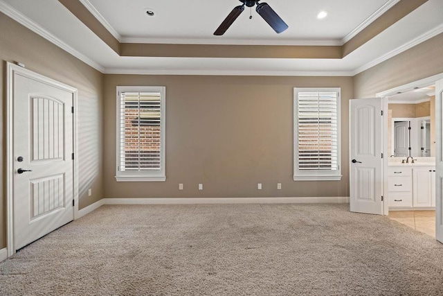 unfurnished bedroom with a raised ceiling, crown molding, sink, and light carpet