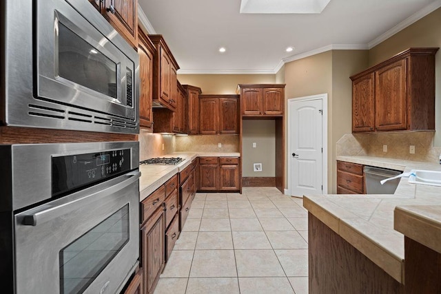 kitchen featuring crown molding, stainless steel appliances, tasteful backsplash, and light tile patterned floors