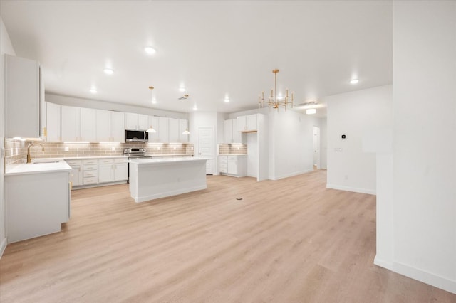 kitchen featuring sink, white cabinetry, backsplash, stainless steel appliances, and a kitchen island