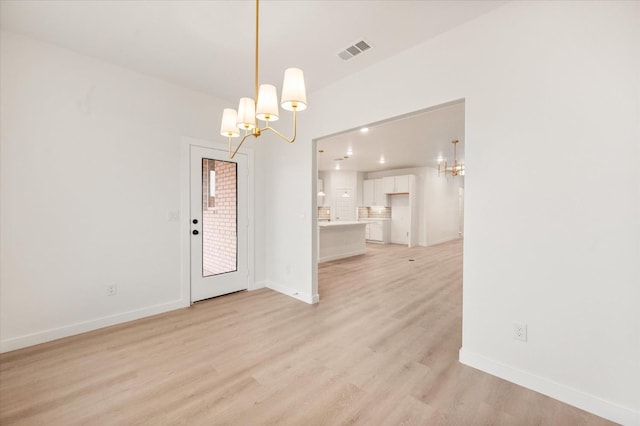 empty room with a chandelier and light wood-type flooring