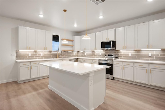 kitchen featuring a center island, light hardwood / wood-style flooring, pendant lighting, stainless steel appliances, and white cabinets