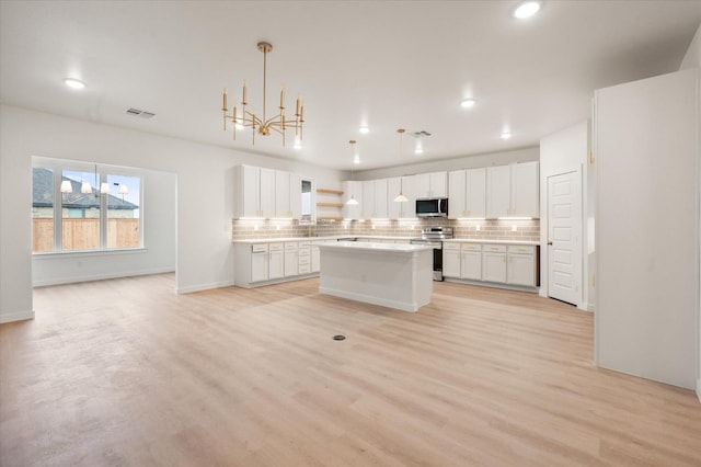 kitchen featuring white cabinetry, a center island, light hardwood / wood-style flooring, appliances with stainless steel finishes, and decorative backsplash