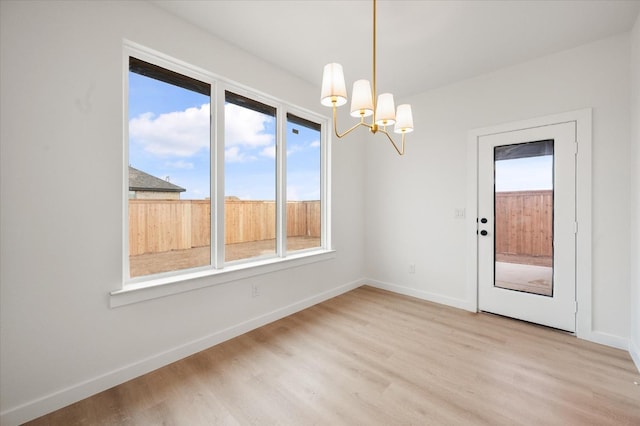 unfurnished dining area with a chandelier and light hardwood / wood-style floors