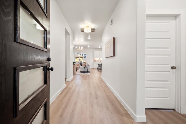 corridor featuring light hardwood / wood-style floors and a chandelier