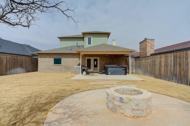 3713 128th St, Lubbock, TX 79423 - back of property with a hot tub, a patio area, a fenced backyard, an outdoor fire pit, and brick siding