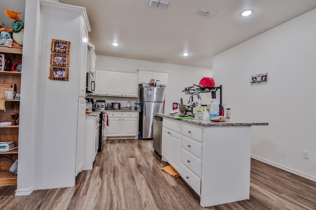 kitchen with white cabinetry, stainless steel appliances, a center island with sink, and light hardwood / wood-style flooring