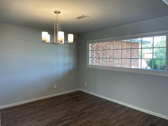 empty room featuring dark hardwood / wood-style floors and a chandelier