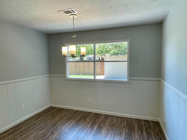 spare room with dark hardwood / wood-style floors, a notable chandelier, and a textured ceiling