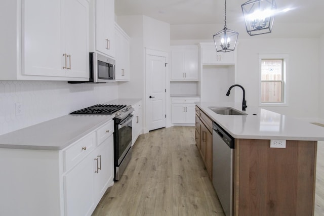 kitchen featuring stainless steel appliances, white cabinetry, a kitchen island with sink, and sink