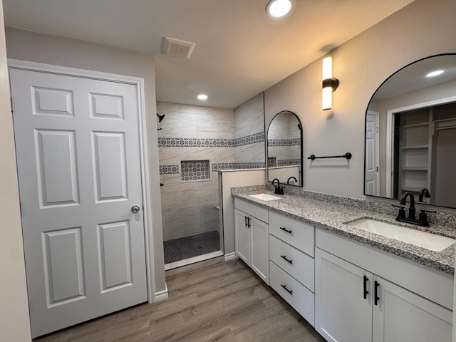 bathroom with tiled shower, vanity, and hardwood / wood-style floors