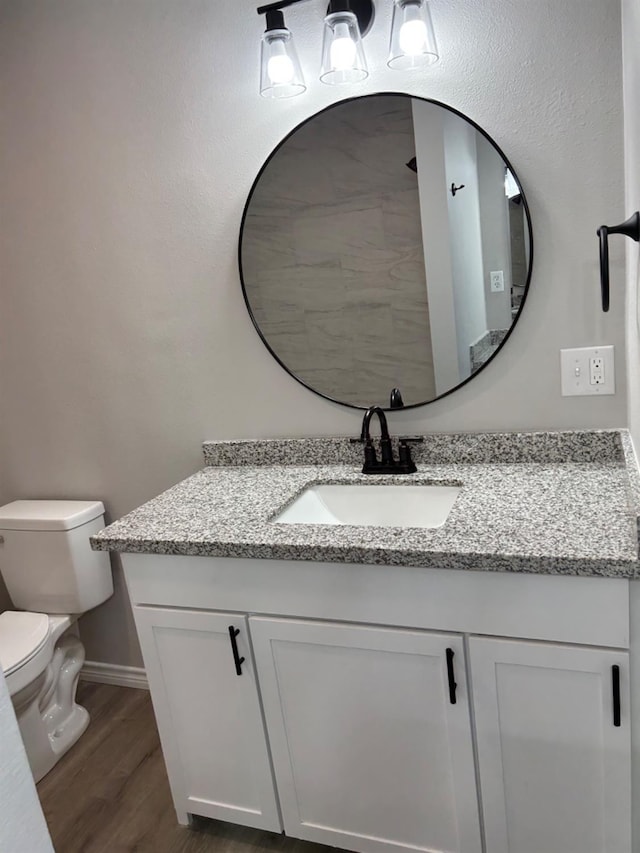 bathroom featuring vanity, hardwood / wood-style flooring, and toilet