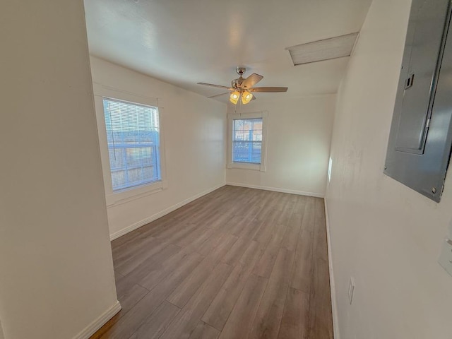 empty room featuring ceiling fan, electric panel, and light hardwood / wood-style floors