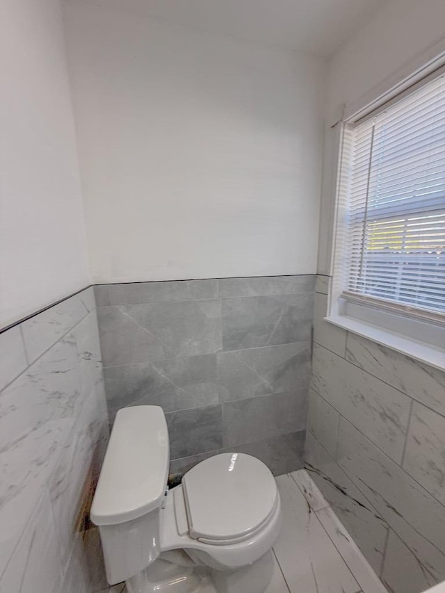 bathroom featuring toilet and tile walls