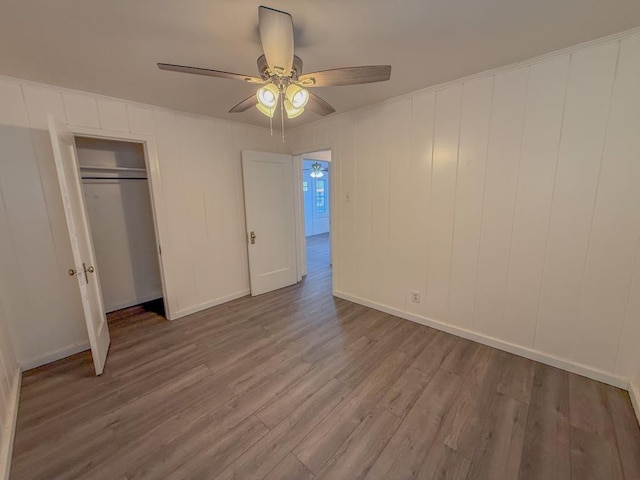 unfurnished bedroom featuring hardwood / wood-style floors, ceiling fan, and a closet