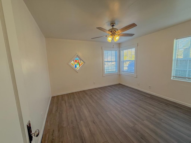 empty room featuring a healthy amount of sunlight, hardwood / wood-style floors, and ceiling fan