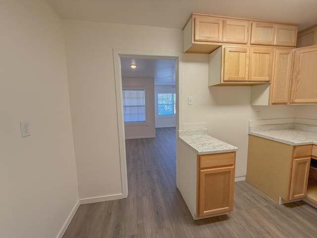 kitchen featuring light brown cabinets, light stone counters, and light wood-type flooring